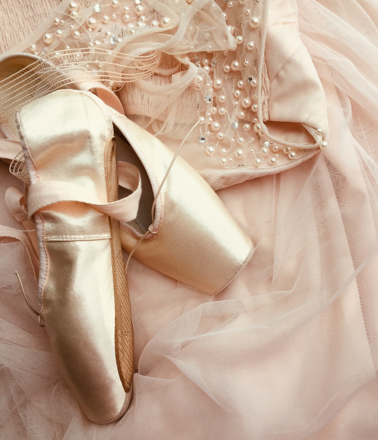 pair of ballet flats laying on pink ballet dress